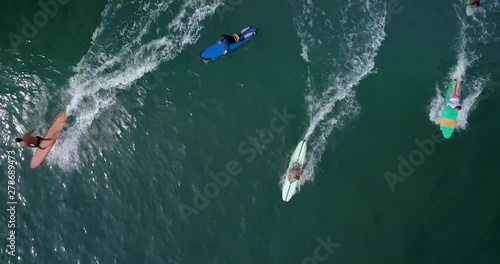 Cinematic aerial drone footage of sporty young surfer couple with long surf board paddle in ocean to surfing lineup. Modern active lifestyle. Water sport adventure camp. Extreme on summer vacation. photo