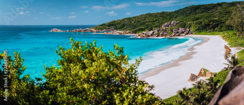 Panorama of epic Grand Anse Beach in La Digue island, Seychelles. White sand beach, big ocean waves and unique granite rocks along coastline. Summer vacation and holiday travel concept photo