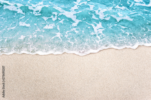 Soft blue ocean wave on clean sandy beach background