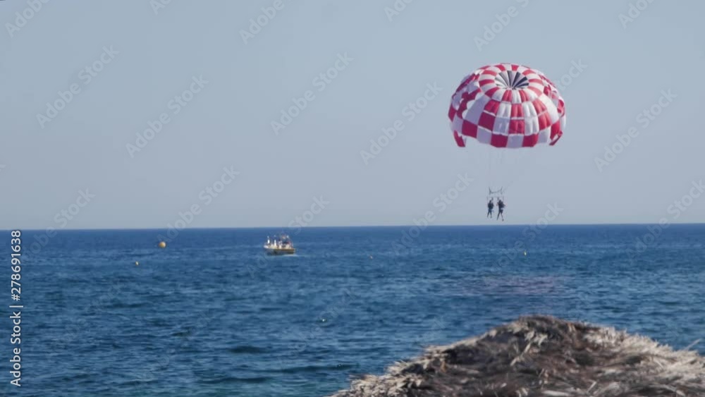 Parasailing Couple From a Boat Landing On The Ocean by The Island of Santorini at Perissa Beach Parasailing Couple From a Boat Landing On The Ocean by The Island of Santorini at Perissa Beach