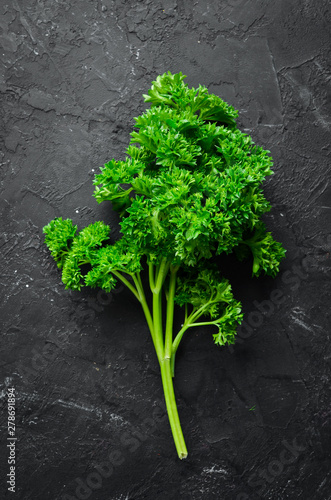 Fresh green parsley. Spices and herbs. On a black stone background. Top view. Free space for your text.