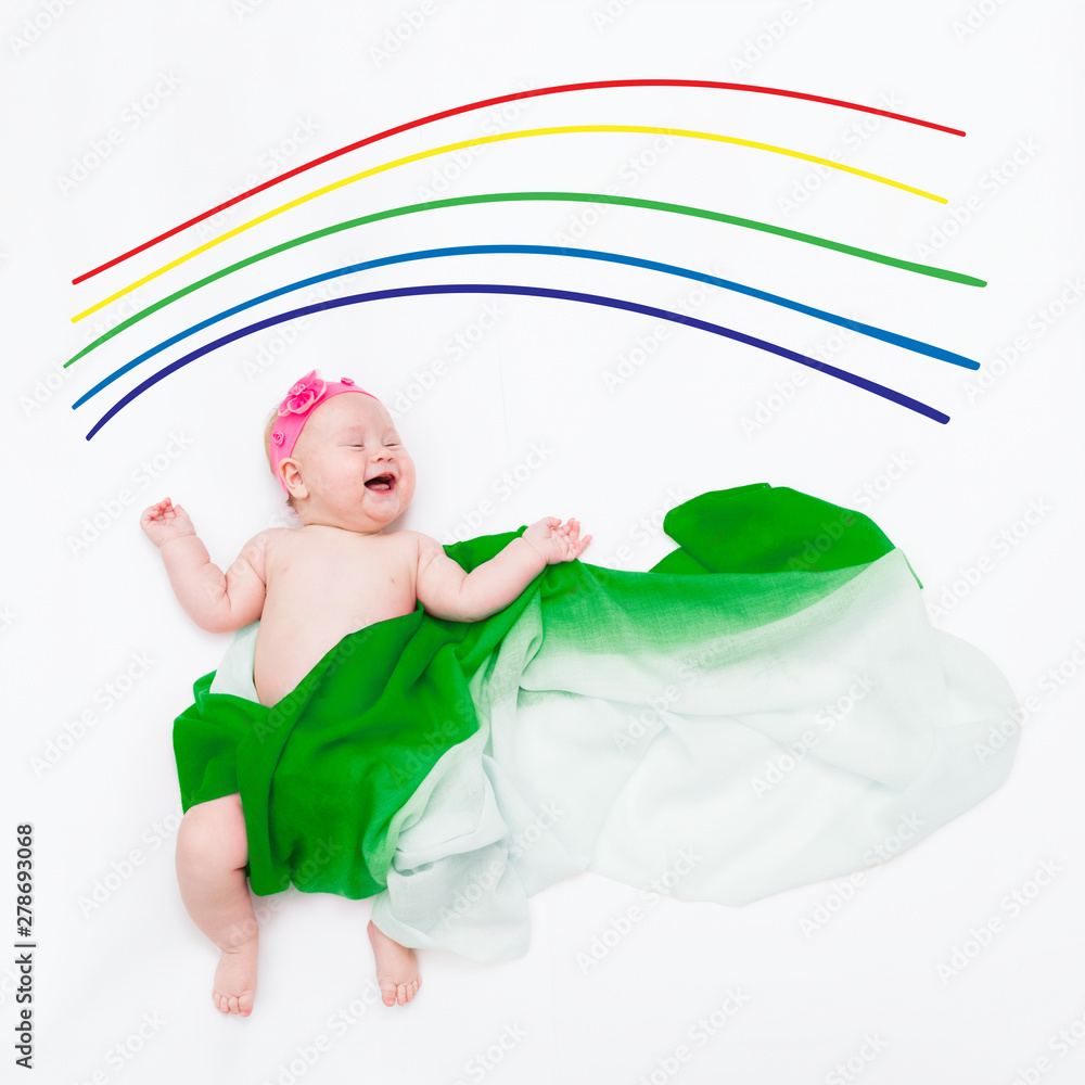 top view of cute infant laughing baby wrapped in a green scarf depicting a cloud under the painted rainbow top view of cute infant laughing baby wrapped in a green scarf depicting a cloud under the painted rainbow