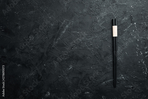 Wooden chopsticks on a black stone background. Top view. Free space for your text. photo