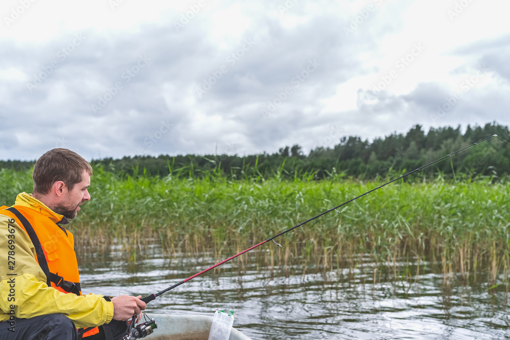Fisherman sitting in an old wooden boat and fishing on a cloudy day. Fisherman sitting in an old wooden boat and fishing on a cloudy day.