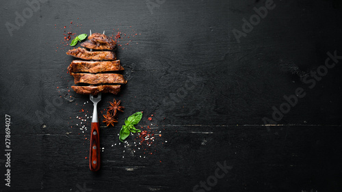 Pork steak on the fork. On a wooden background. Top view. Free space for your text.