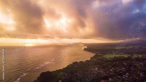Beautiful Aerial timelapse in motion or hyperlapse on ocean shoreline in Kauai, Hawaii at sunrise with dramatic rainclouds and sunlight