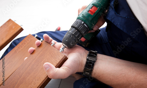 The man is assembling wooden furniture in home