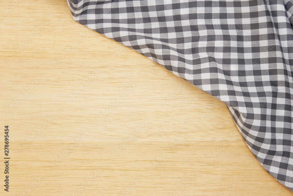 Wrinkled grey gingham fabric on rustic light brown wood background, with copy space. Wrinkled grey gingham fabric on rustic light brown wood background, with copy space.