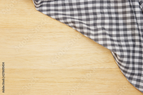 Wrinkled grey gingham fabric on rustic light brown wood background, with copy space. 