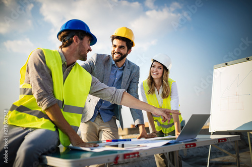 Team of architects and engineer in group on construciton site check documents and business workflow photo