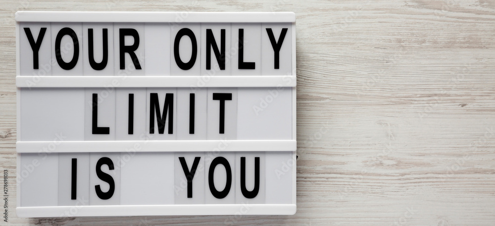 Modern board with 'Your only limit is you' words on a white wooden background, top view. From above, flat lay, overhead. Space for text. Modern board with 'Your only limit is you' words on a white wooden background, top view. From above, flat lay, overhead. Space for text.