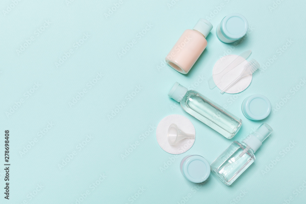 Group of small bottles for travelling on blue background. Copy space for your ideas. Flat lay composition of cosmetic products. Top view of cream containers with cotton pads Group of small bottles for travelling on blue background. Copy space for your ideas. Flat lay composition of cosmetic products. Top view of cream containers with cotton pads