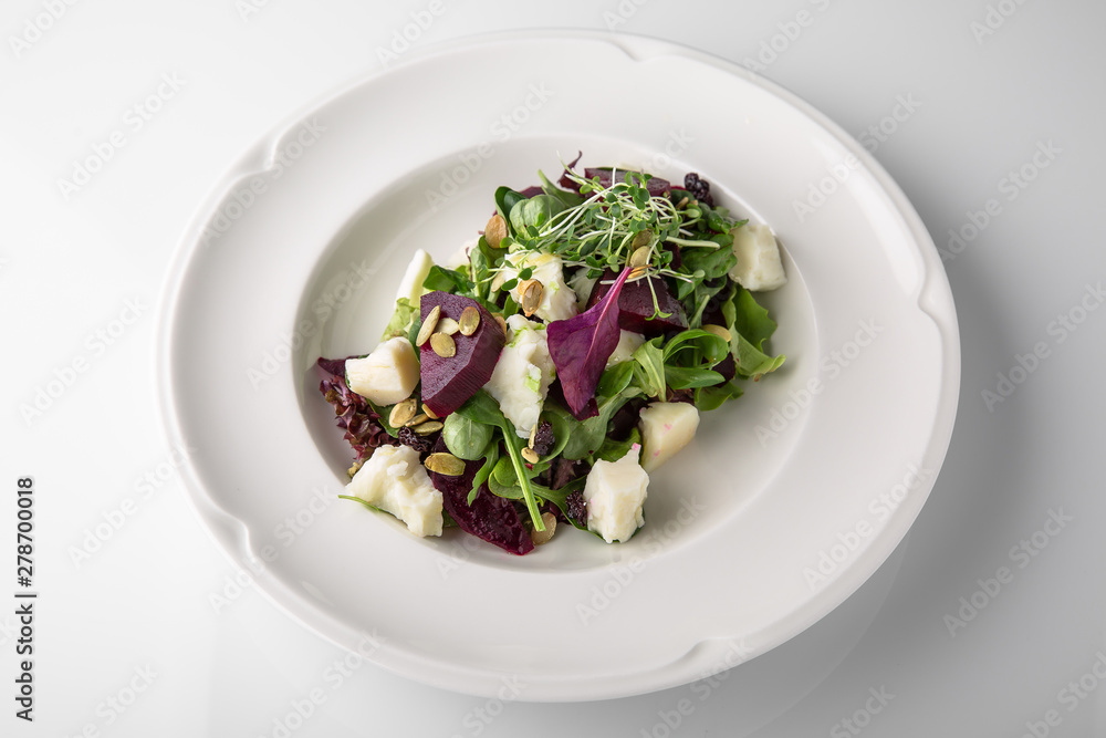 Nutritious, healthy, vitamin, dietary salad of boiled beets, cheese, arugula and nuts. Banquet festive dishes. Gourmet restaurant menu. White background. Nutritious, healthy, vitamin, dietary salad of boiled beets, cheese, arugula and nuts. Banquet festive dishes. Gourmet restaurant menu. White background.
