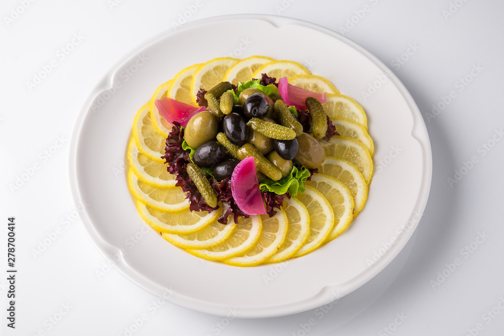 Appetizer of pickles, assorted olives and lemon. Banquet festive dishes. Gourmet restaurant menu. White background. Appetizer of pickles, assorted olives and lemon. Banquet festive dishes. Gourmet restaurant menu. White background.
