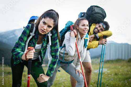 Gorup of friends climbing up hill, with backpacks and climbing stick © NDABCREATIVITY