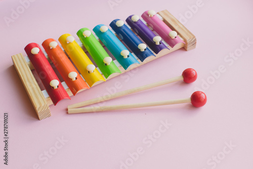 Rainbow Colored Wooden Toy Xylophone on pink bacground. toy glockenspiel made of metal and wood