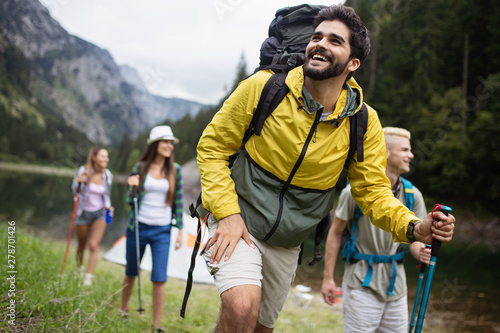 Smiling friends walking with backpacks. Adventure, travel, tourism, hike and people concept.