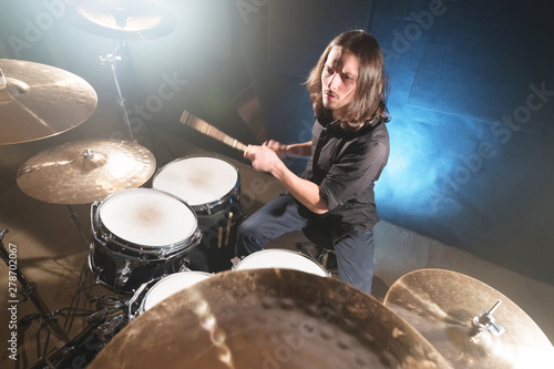 Portrait of a long-haired drummer with chopsticks in his hands sitting behind a drum set Fototapete