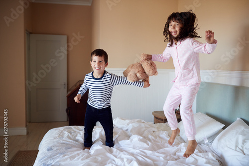 Εκτύπωση καμβά Brother and sister having fun bouncing on their parentsâ€™ bed in their pyjamas,