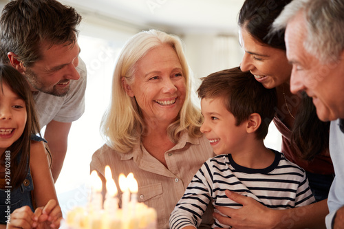 Four year old white boy and his family celebrating with a birthday cake and lit candles  close up
