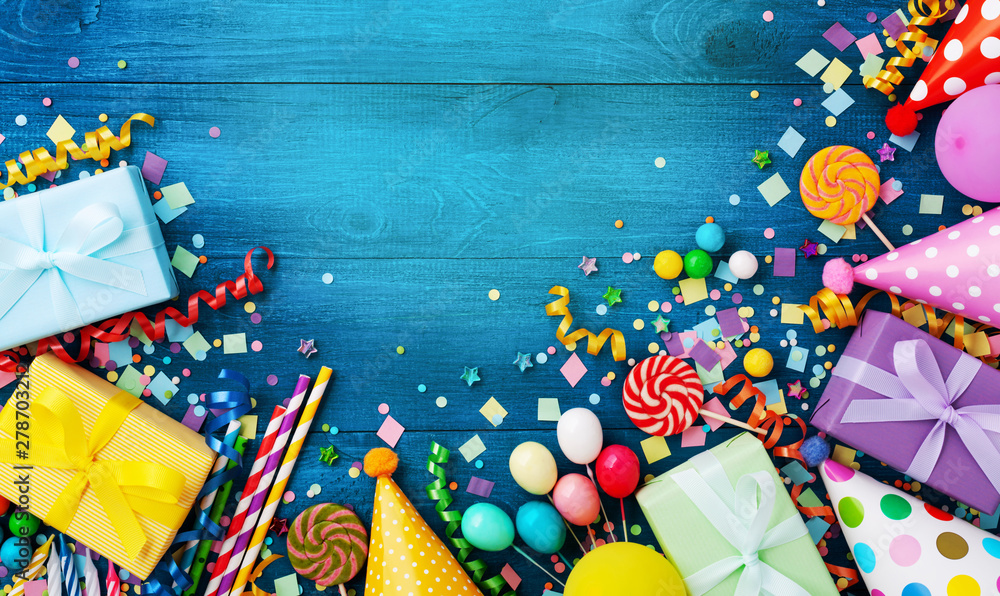 Obraz premium Gift or present boxes, holiday supplies and confetti on blue wooden table top view. Birthday party greeting card.
