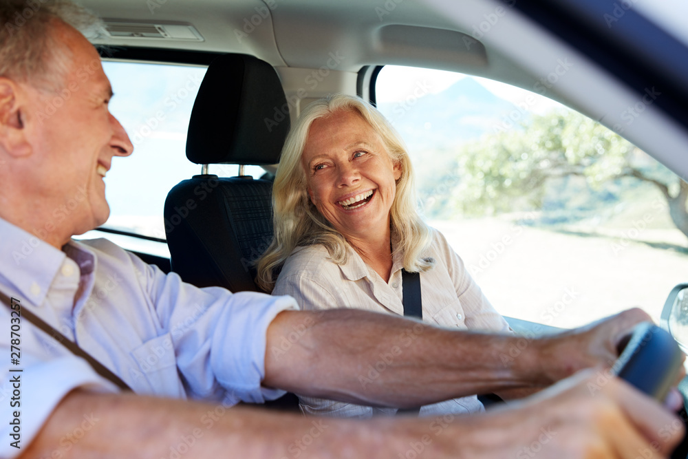 Senior white couple driving in their car, looking at each other, side view, close up Senior white couple driving in their car, looking at each other, side view, close up