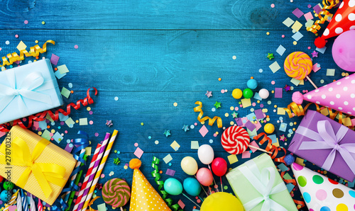 Gift or present boxes, holiday supplies and confetti on blue wooden table top view. Birthday party greeting card.