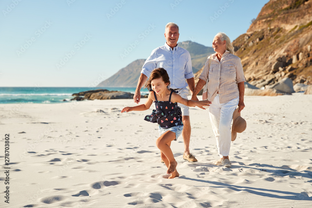 Senior white couple and their granddaughter walking on a sunny beach, close up