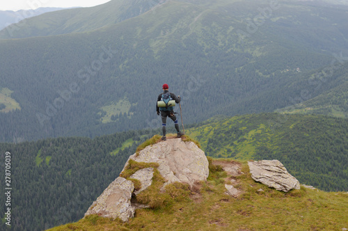 Male tourist on top of gray mountain in fog in summer.