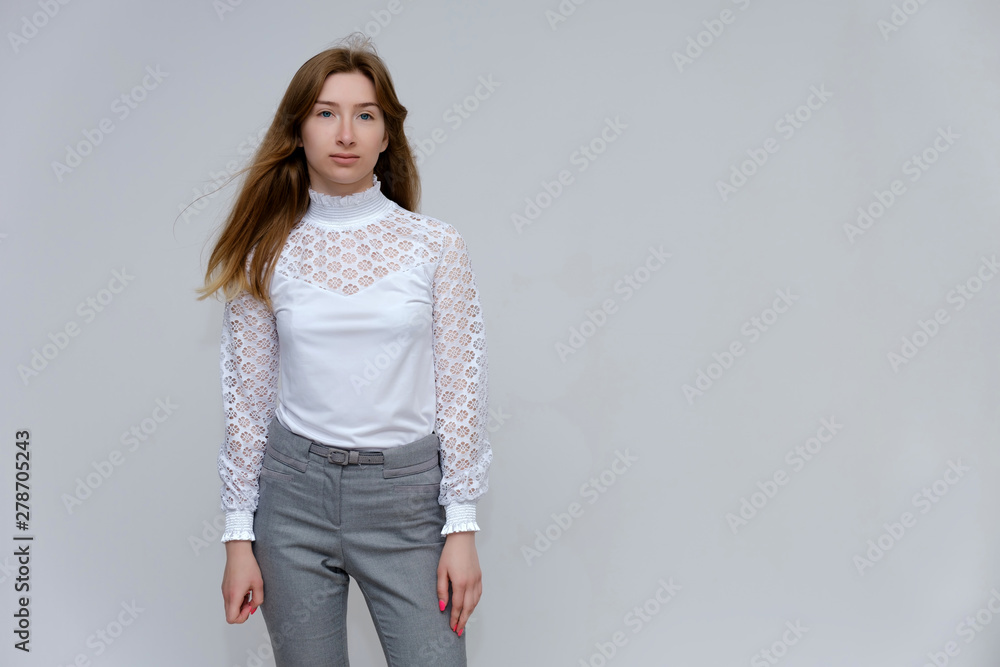 Portrait of a knee-high young pretty brunette girl woman with beautiful long hair on a white background in a white jacket and gray pants. He talks, shows his hands with emotions in various poses. Portrait of a knee-high young pretty brunette girl woman with beautiful long hair on a white background in a white jacket and gray pants. He talks, shows his hands with emotions in various poses.