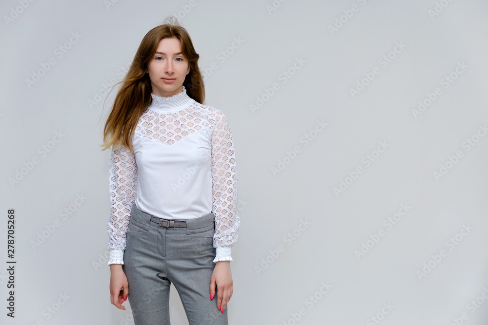 Portrait of a knee-high young pretty brunette girl woman with beautiful long hair on a white background in a white jacket and gray pants. He talks, shows his hands with emotions in various poses. Portrait of a knee-high young pretty brunette girl woman with beautiful long hair on a white background in a white jacket and gray pants. He talks, shows his hands with emotions in various poses.
