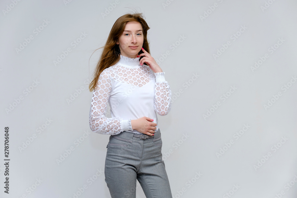 Portrait of a knee-high young pretty brunette girl woman with beautiful long hair on a white background in a white jacket and gray pants. He talks, shows his hands with emotions in various poses. Portrait of a knee-high young pretty brunette girl woman with beautiful long hair on a white background in a white jacket and gray pants. He talks, shows his hands with emotions in various poses.