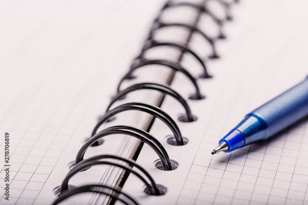 Opened notepad in a cage with an automatic plastic ballpoint pen close-up. toned Opened notepad in a cage with an automatic plastic ballpoint pen close-up. toned