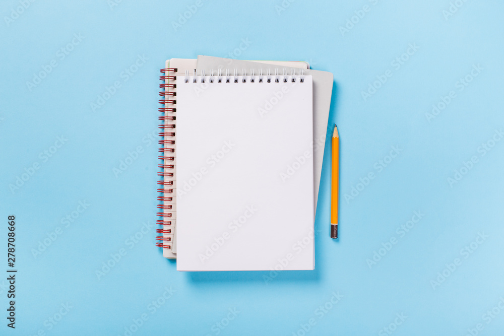 school notebook on a blue background, spiral notepad on a table - obrazy, fototapety, plakaty 