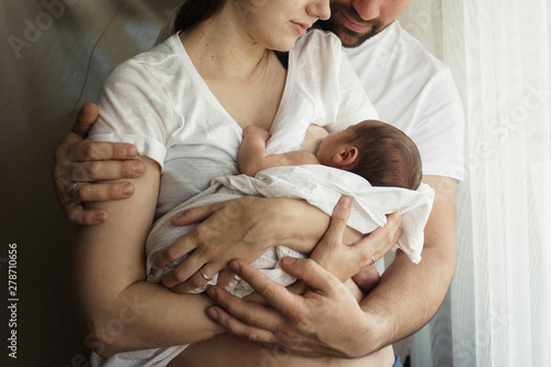  Father and mother with a newborn son. New young multi-generation family. Breast-feeding