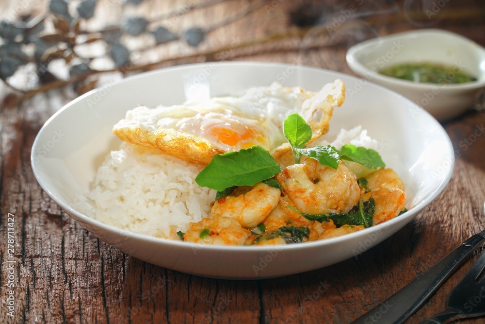 Thai food : Kaphrao Kung is Stirred and fried shrimps with holy basil and chilies served on steamed rice and fried egg. Shooting in studio for advertising. Thai and Asian food concept.