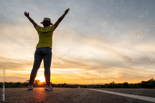 Women wearing t-shirts, jeans, sneakers and hats at sunset, standing along the highway to travel, Happy mood, Vacation concept