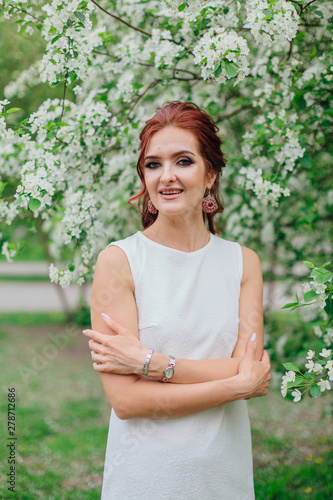 Charming woman wearing beautiful white dress under the apple tree