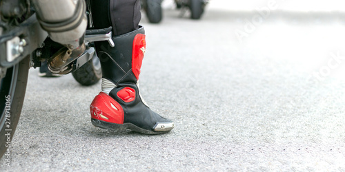 closeup leg of a motorcycle racer with with soft-focus and over light in the background