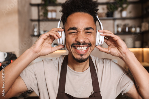 Happy young man barista standing at the coffee shop