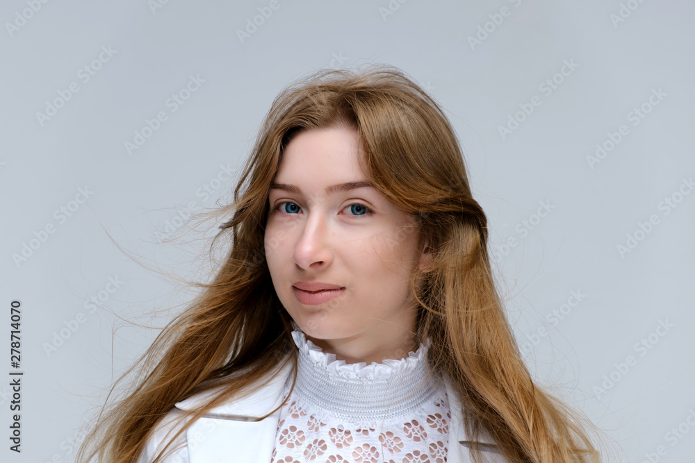 Close-up portrait of a young pretty brunette girl woman with beautiful long hair on a white background in a white jacket. He talks, smiles, shows his hands with emotions in various poses. Close-up portrait of a young pretty brunette girl woman with beautiful long hair on a white background in a white jacket. He talks, smiles, shows his hands with emotions in various poses.