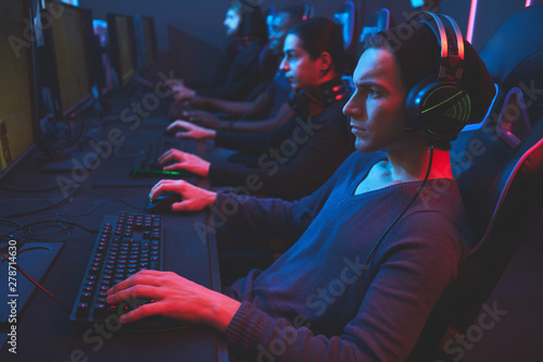 Fotografie Serious concentrated esports player concentrated on game wearing wired headset s