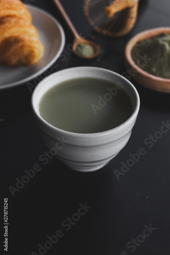 matcha green tea latte on black table with soft-focus and over light in the background