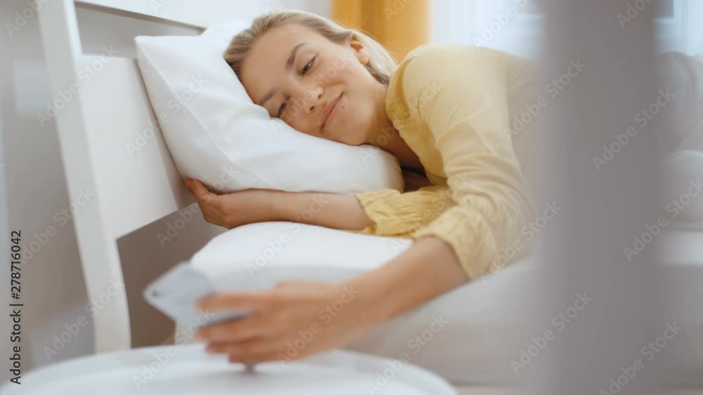 Beautiful blonde woman wearing pajama using phone in her bedroom. Beautiful blonde woman wearing pajama using phone in her bedroom.