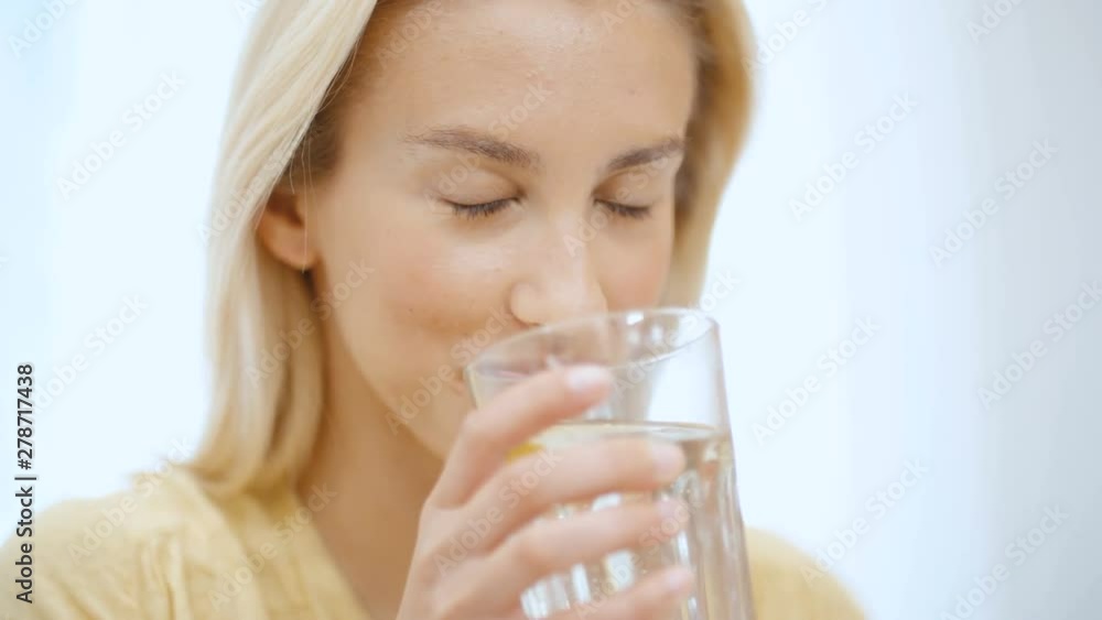 Portrait of young woman in pajama holding water while sitting on a bed. Portrait of young woman in pajama holding water while sitting on a bed.