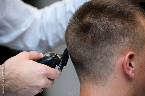 Barber cutting customer’s hair with a hairclipper