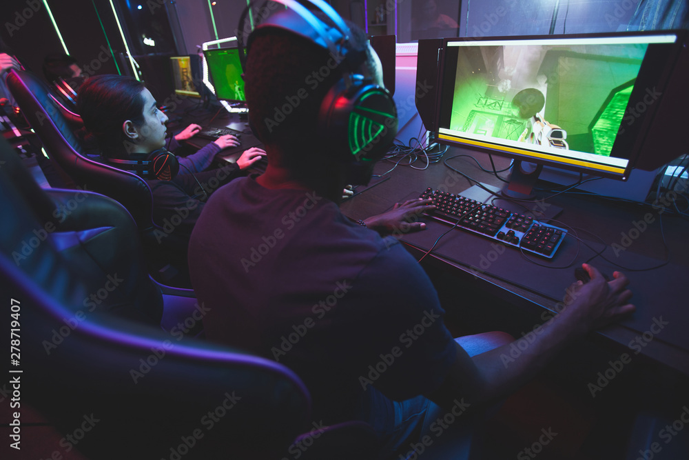Orbit Meaningful wreath Rear view of addicted gamers sitting at table and looking at monitors while  playing online multiplayer game Stock Photo | Adobe Stock