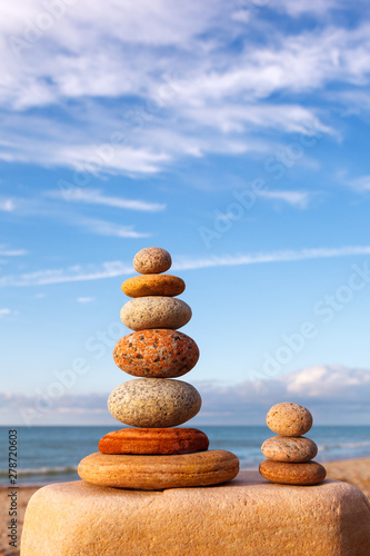 Rock zen pyramid of white and pink stones on a background of blue sky and sea.