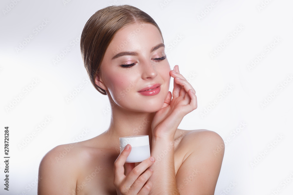 Beautiful woman applying moisturizing cream on her face. Girl holding cream in her hand .Spa and face care Beautiful woman applying moisturizing cream on her face. Girl holding cream in her hand .Spa and face care