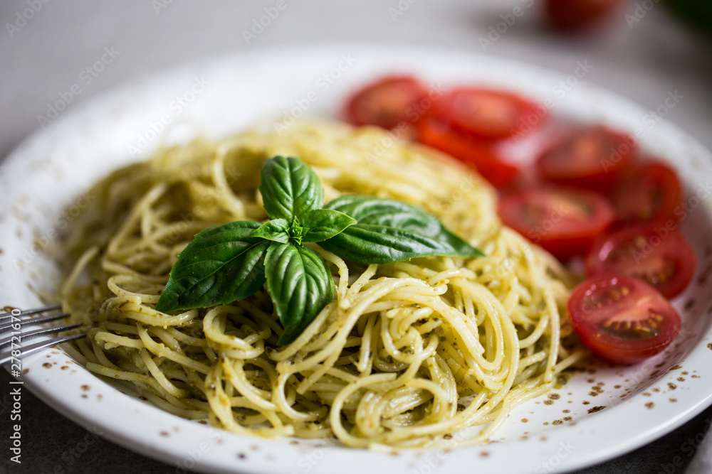 Spaghetti with homemade pesto sauce, basil leaves and  tomatoes/
